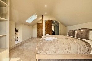 A bedroom with a large bed, a skylight, and a wooden wardrobe. - Countryside Cottage - 2 En-Suites - Parking for 2 (Talbenny)