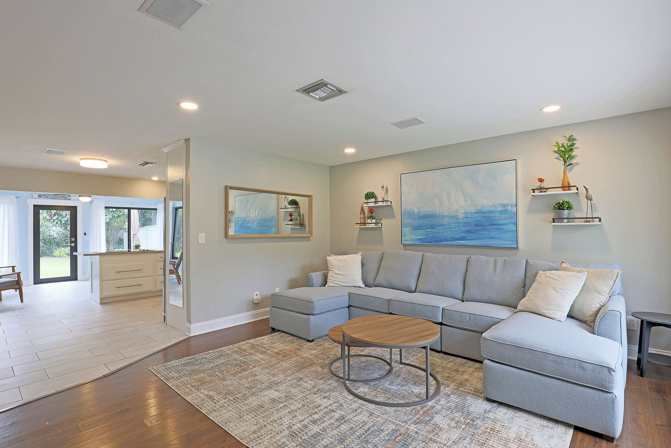 A modern living room with a sectional sofa, a coffee table, and a large painting.