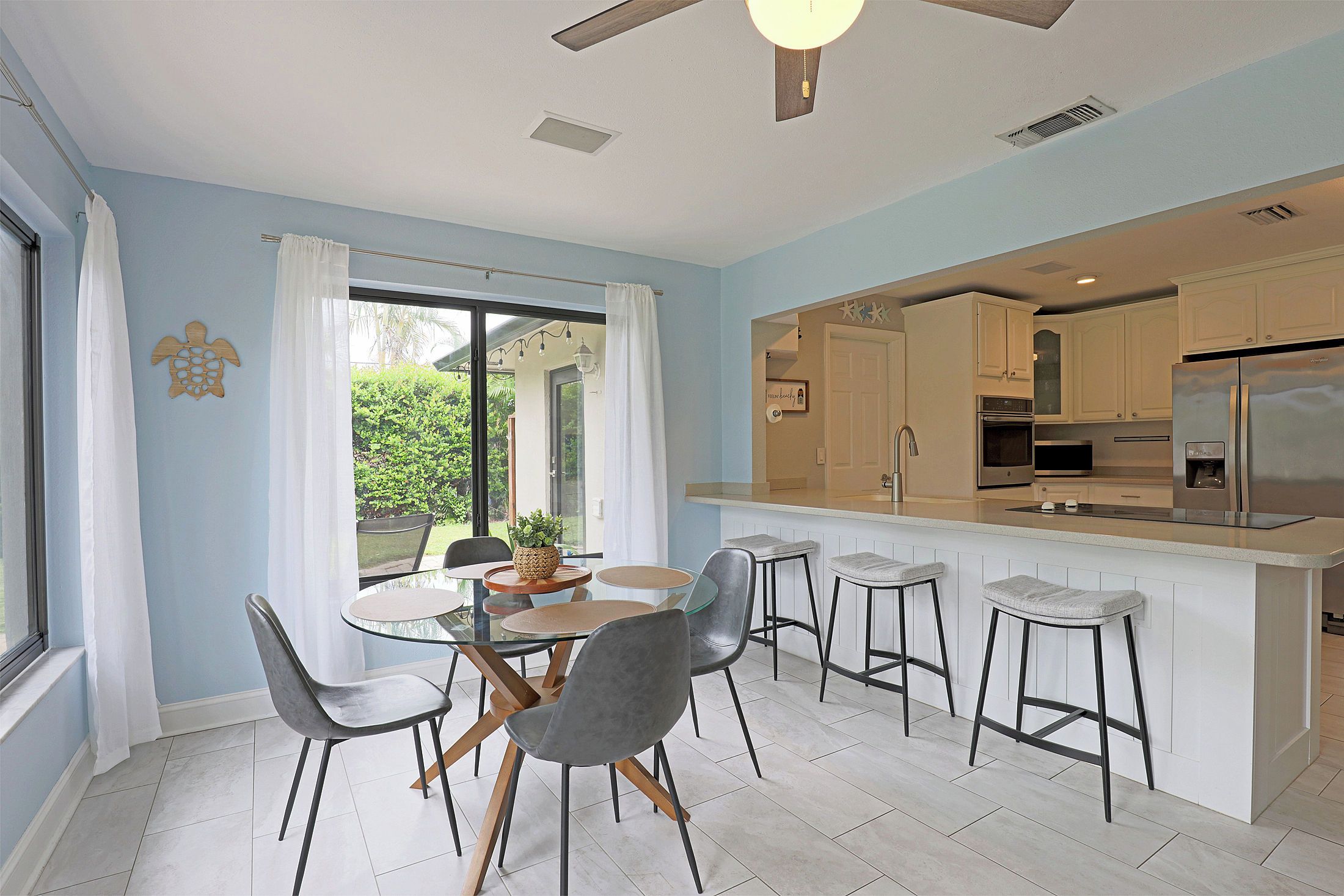 A modern kitchen with a central island, bar stools, and a dining area with chairs.