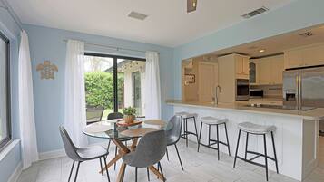 A modern kitchen with a central island, bar stools, and a dining area with chairs.