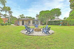 A backyard with a fire pit, outdoor seating, and a swing set. - Cozy 2-bedroom house near downtown Bonita Springs (Bonita Springs)