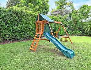 A wooden playground structure with a slide and climbing ladder in a grassy area. - Cozy 2-bedroom house near downtown Bonita Springs (Bonita Springs)