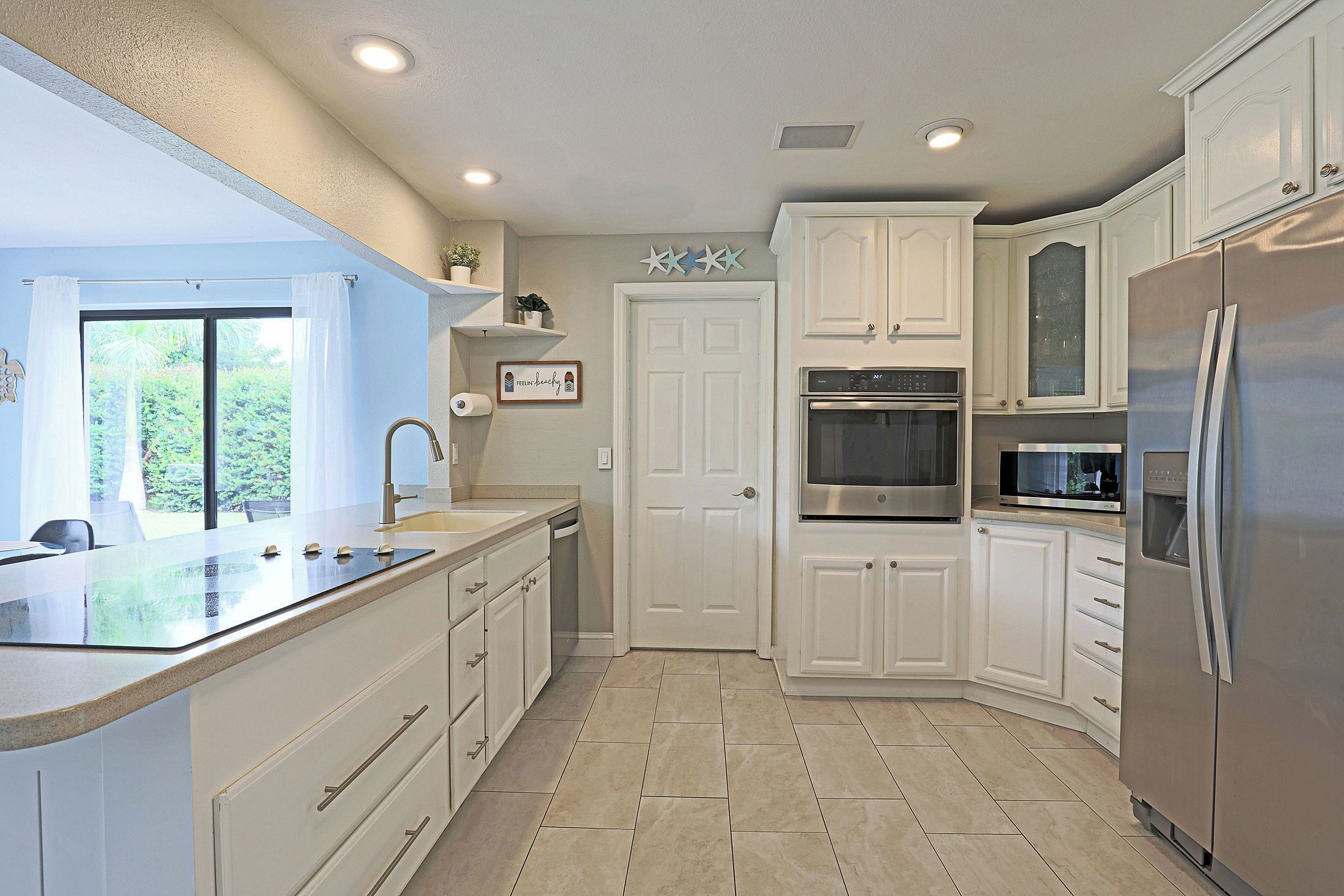 A modern kitchen with white cabinetry, a stainless steel refrigerator, an oven, and a microwave.