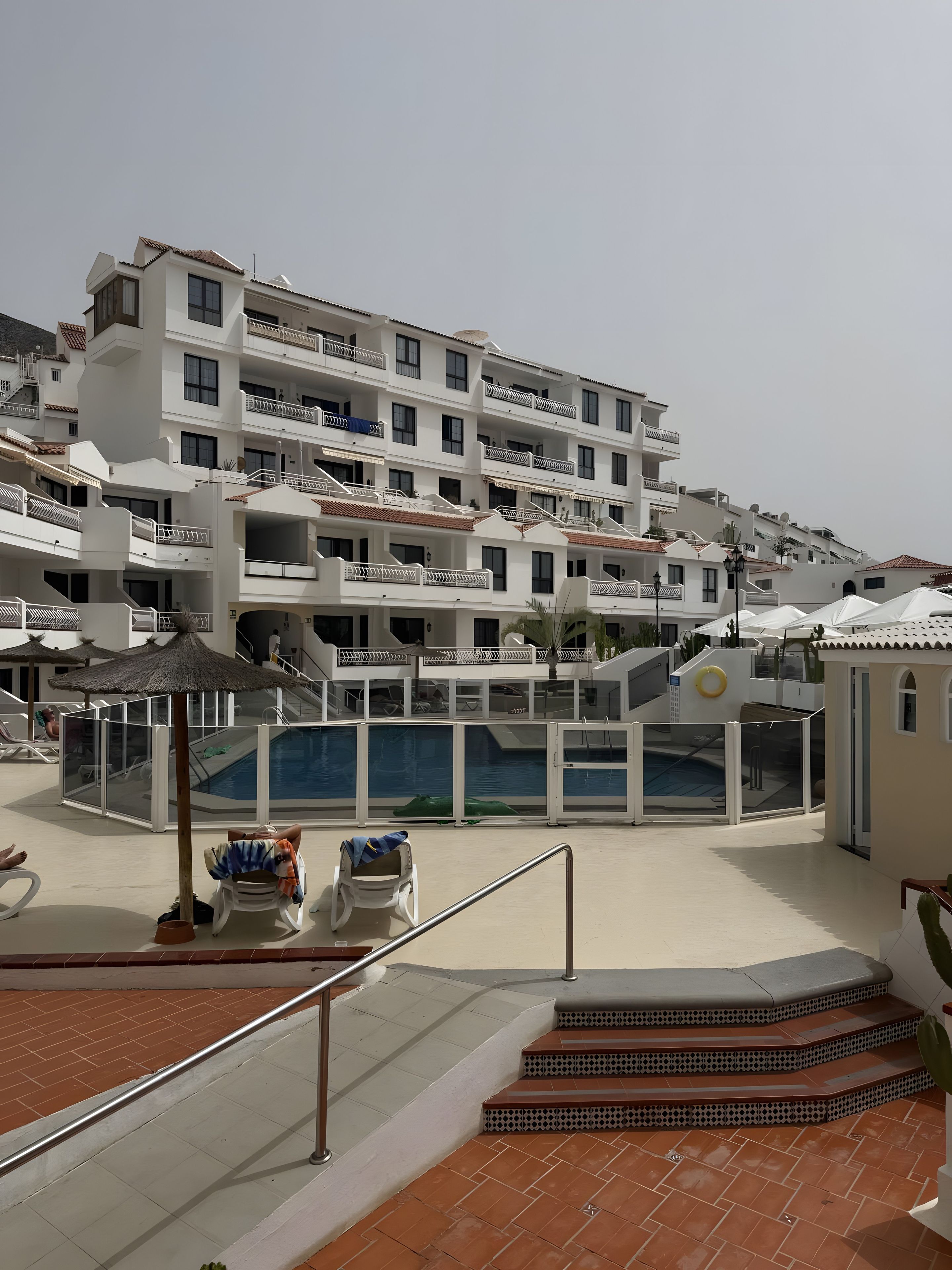 Et resort med flere balkoner, en swimmingpool og en trappe til de øvre etager.