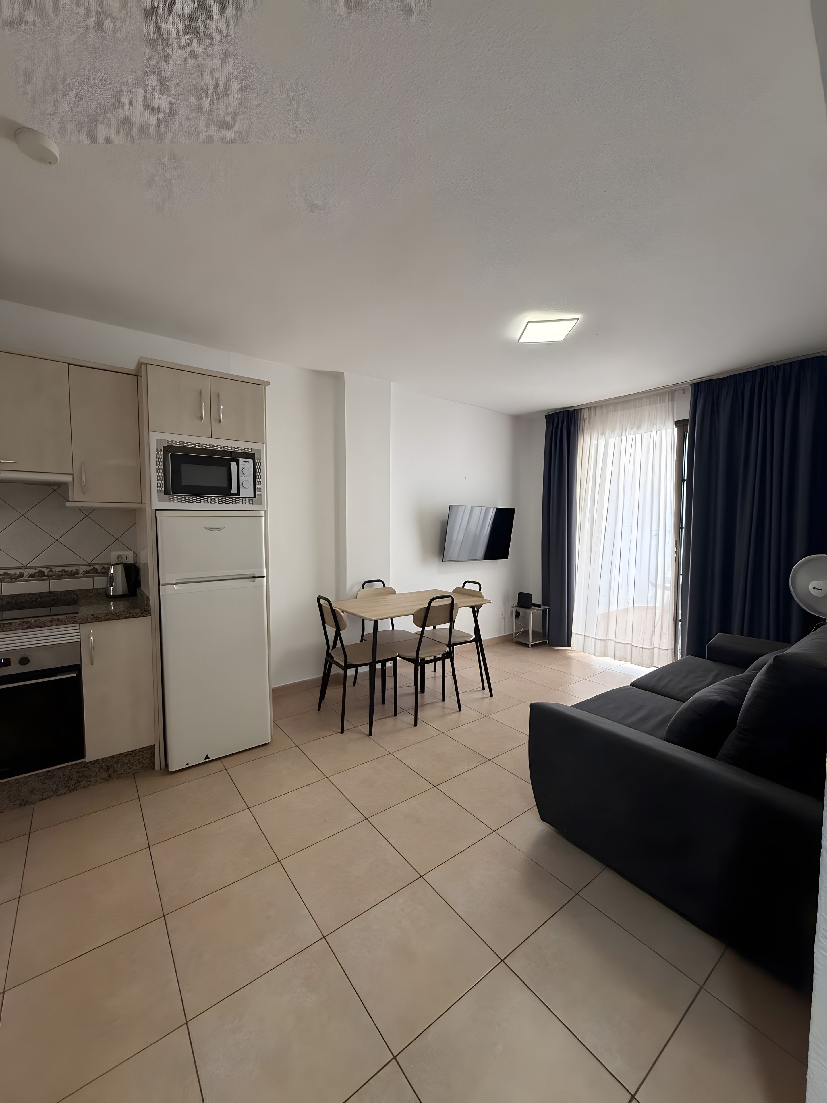 Een compacte leefruimte met een kitchenette, een eethoek en een zithoek.