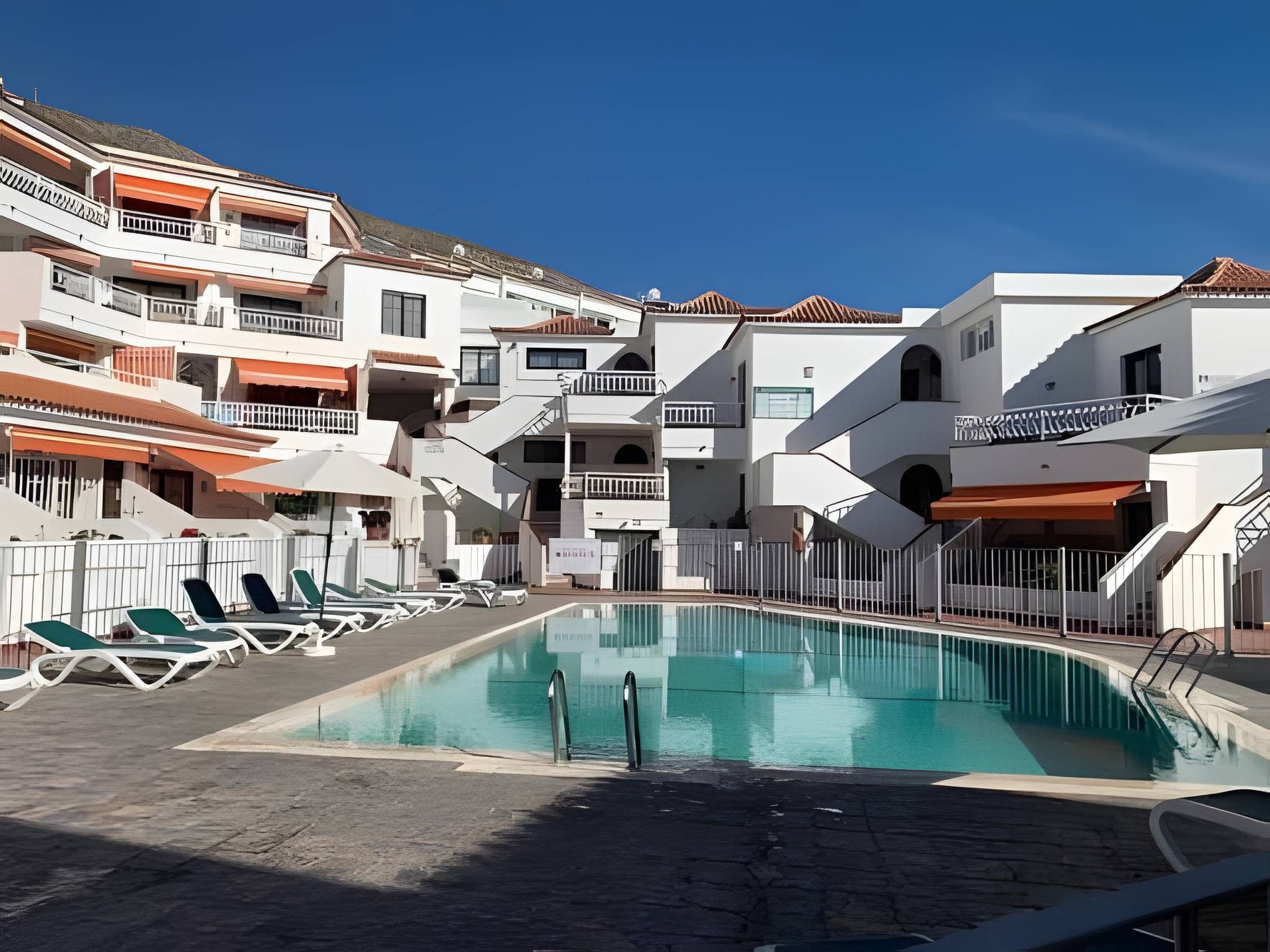 A swimming pool with lounge chairs and a clear blue sky.