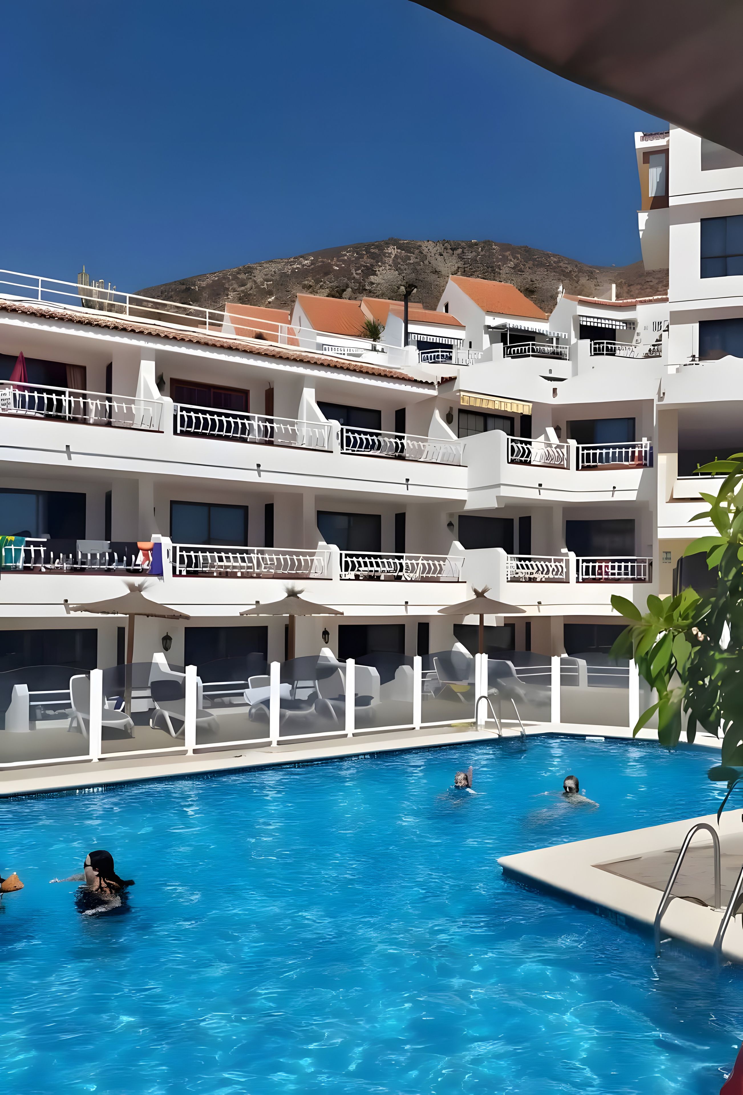 Un hôtel à plusieurs étages doté d’une piscine, d’un espace extérieur aménagé et offrant une vue sur les montagnes.