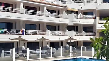 Un hôtel à plusieurs étages doté d’une piscine, d’un espace extérieur aménagé et offrant une vue sur les montagnes.