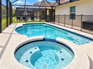 A swimming pool with a hot tub, surrounded by a covered patio area.