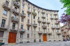 A multi-story building with balconies, a central entrance, and a street view. - In the vibrant heart of Turin, this flat is all about atmosphere: a spacious, light-filled living room with a fully equipped kitchen, two double bedrooms, a sofa bed and two balconies (one overlooking Largo Montebello, the other a more intimate internal  (Torino)