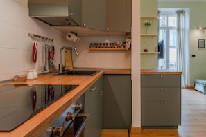 A modern kitchen with a wooden countertop, built-in oven, and grey cabinetry. - In the vibrant heart of Turin, this flat is all about atmosphere: a spacious, light-filled living room with a fully equipped kitchen, two double bedrooms, a sofa bed and two balconies (one overlooking Largo Montebello, the other a more intimate internal  (Torino)