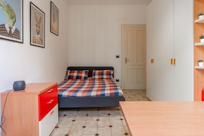 A bedroom with a bed, a desk, a chair, and a door. - In the vibrant heart of Turin, this flat is all about atmosphere: a spacious, light-filled living room with a fully equipped kitchen, two double bedrooms, a sofa bed and two balconies (one overlooking Largo Montebello, the other a more intimate internal  (Torino)