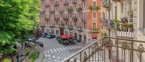 A multi-story building with balconies, a pedestrian crossing, and a street with parked cars.