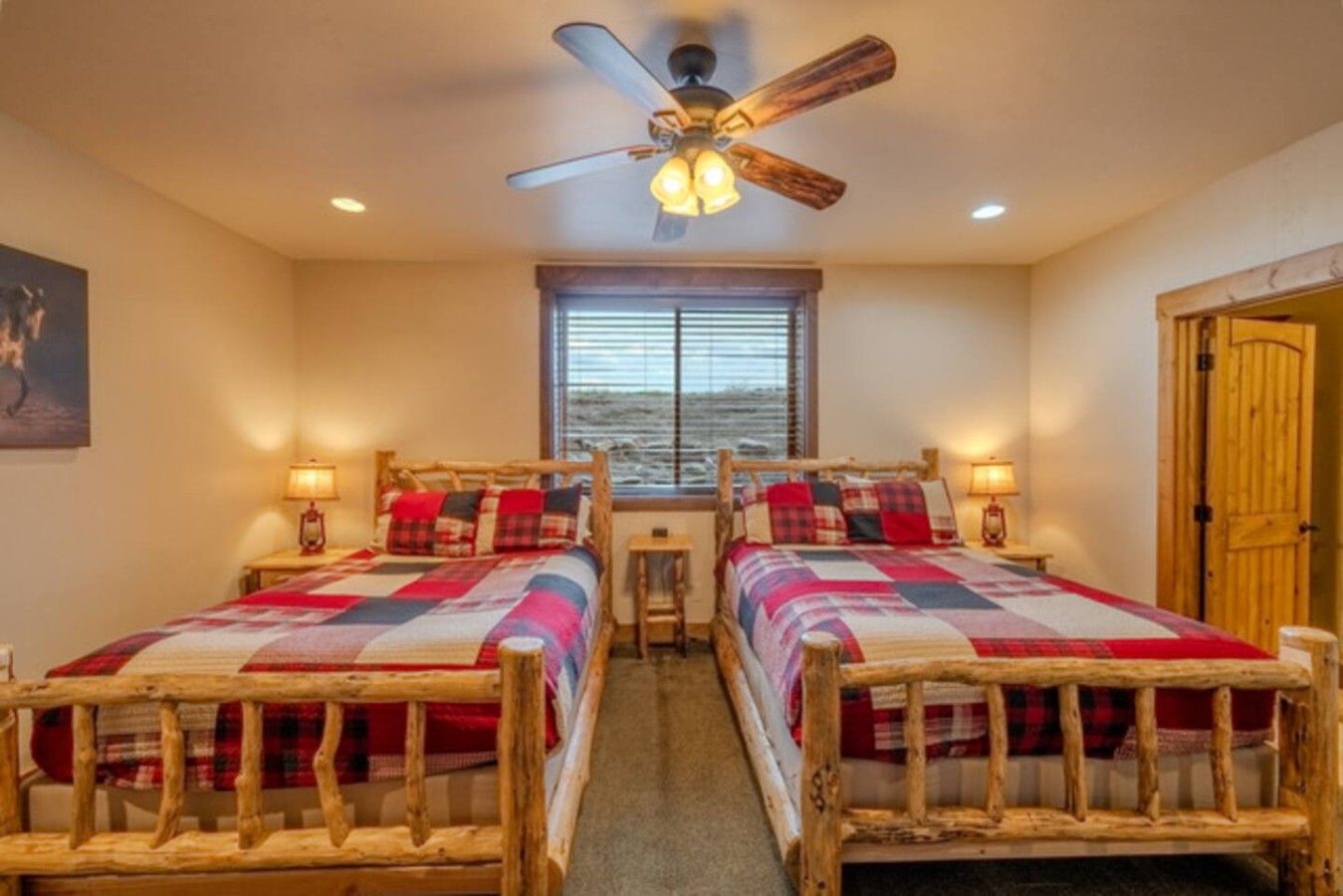 A room with two wooden beds, a ceiling fan, and a window with blinds.