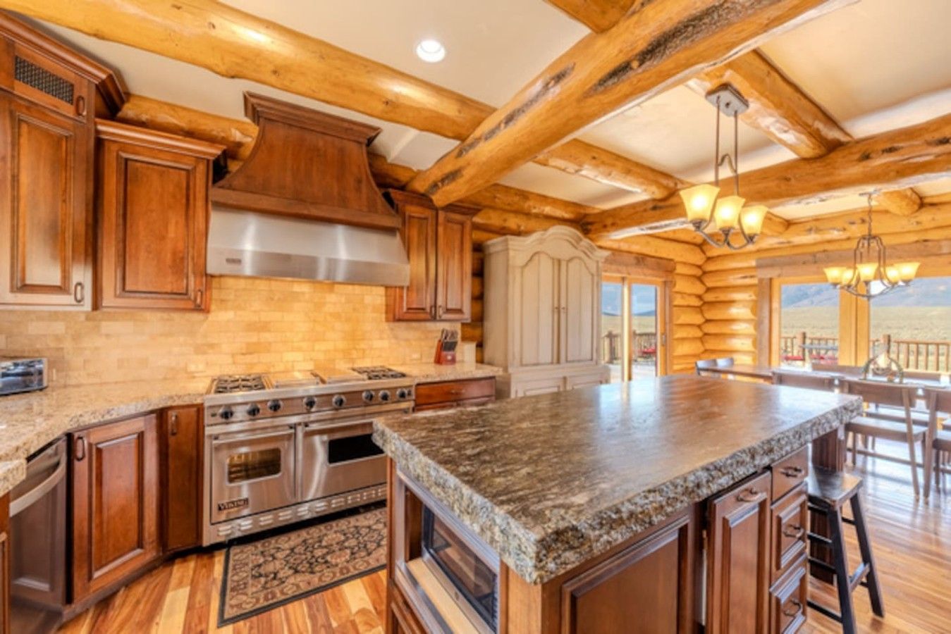 A log cabin-style kitchen with a granite countertop, stainless steel appliances, and wooden cabinets.