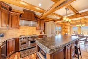 A log cabin-style kitchen with a granite countertop, stainless steel appliances, and wooden cabinets. - Yellowstone Pointe Lodge - Sleeps 30, 20minToYellowstone, Movie Room, Games! (Island Park)