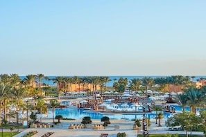 Ein Resort mit mehreren Schwimmbecken, Palmen und Strandstühlen.