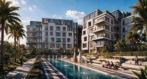 Ein modernes Wohngebäude mit Schwimmbad, Palmen und einem gepflegten Garten.