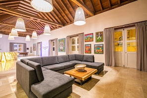 A modern living room with a sectional sofa, a wooden coffee table, and artwork on the walls. - 11 Bedroom Villa in the Old City (Cartagena de Indias)