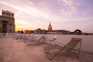 A rooftop terrace with lounge chairs and a view of historic buildings. - 11 Bedroom Villa in the Old City (Cartagena de Indias)