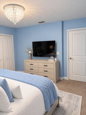 Ein Schlafzimmer mit Bett, Schminktisch, Fernseher und einer Chandelier.