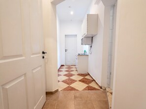 A hallway with a checkered floor leading to a kitchen area with a white cabinet and a sink. - Vienna on Your Doorstep 1BR (Wien)