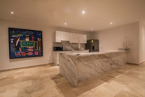 A modern kitchen with marble countertops, white cabinets, and a large island. - Modern 7 Bedroom Mansion in Old City (Cartagena de Indias)