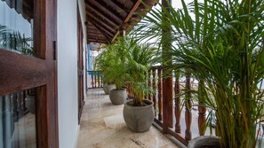 A covered balcony with large potted plants and a tiled floor. - Modern 7 Bedroom Mansion in Old City (Cartagena de Indias)