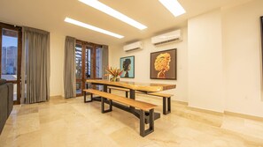 A modern room with a wooden bench, a vase with flowers, and two framed artworks on the wall. - Modern 7 Bedroom Mansion in Old City (Cartagena de Indias)