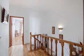 Een houten trap met een leuning, die leidt naar een kamer met een deur en een stoel.