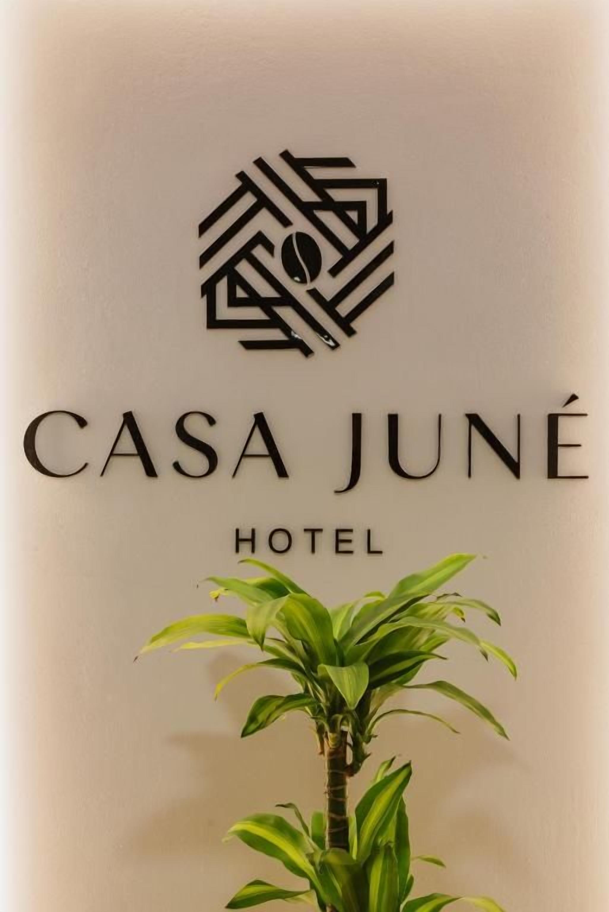 Een bordje voor CASA JUNÉ HOTEL, met een logo boven de naam en een bloempot eronder.