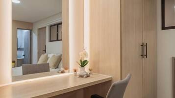 Una habitación moderna con suelo de madera, un escritorio con silla, un espejo grande y un armario.