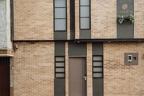 Fachada d'un edifici amb façana de totxins, una porta central i una finestra amb una planta.