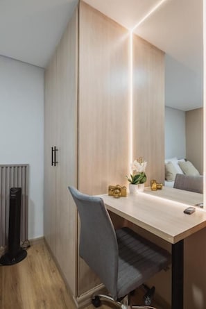 Habitació moderna i compacte amb un armari de fusta, un escriptori amb una cadira i una planta petita sobre l'escriptori.