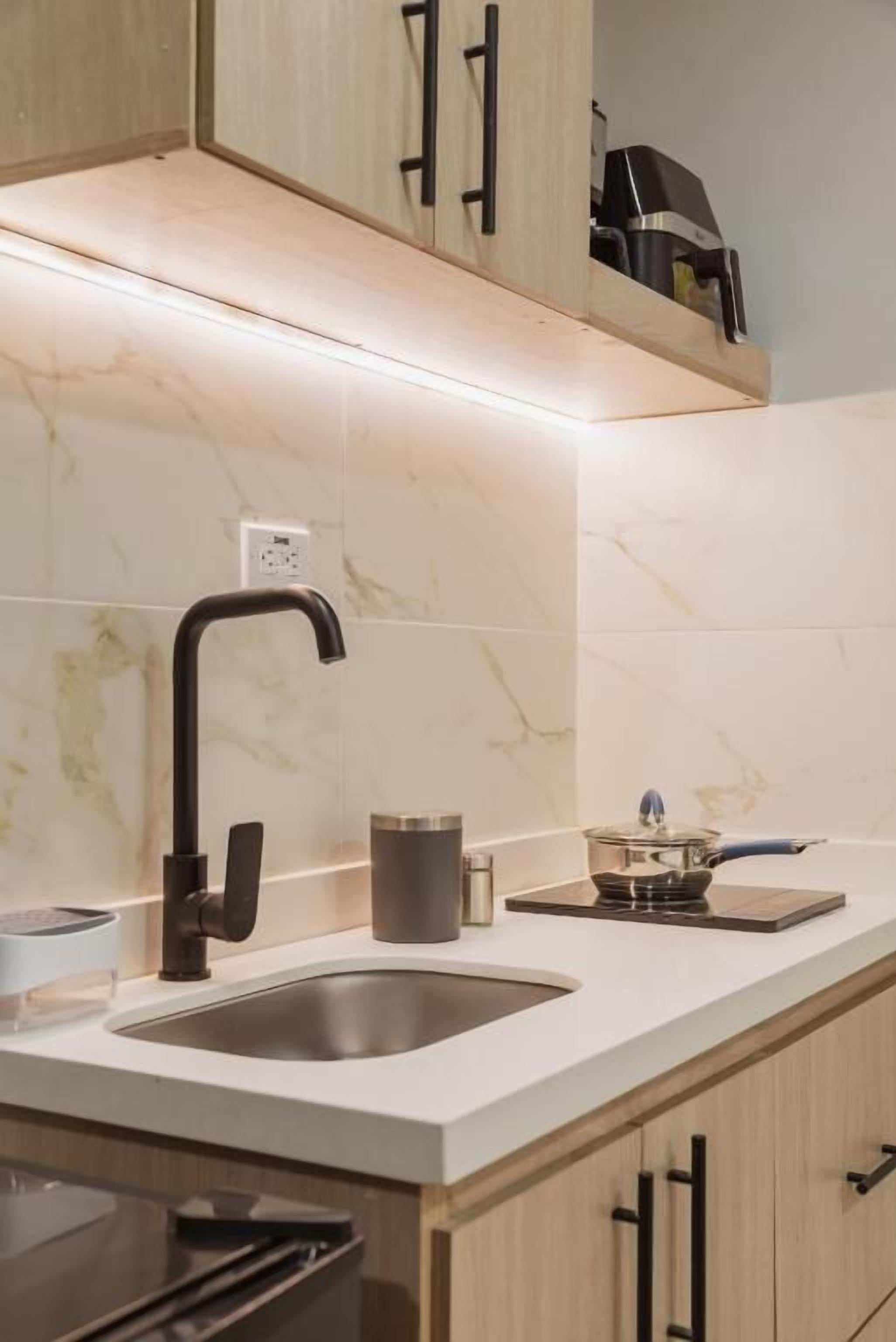 Una cocina moderna con un lavamanos de acero inoxidable, una cafetera y una encimera con un hervidor.