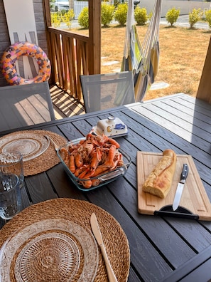 Une table à manger avec un saladier en verre rempli de crevettes, une miche de pain et un couteau posés sur une planche à découper en bois.