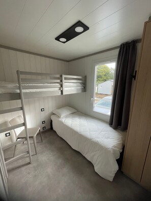 A bunk bed room with a window and a door.