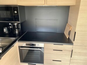 A compact kitchen with a Bosch microwave, coffee maker, and built-in oven.