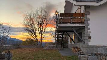 Un bâtiment moderne avec une façade en pierre, une terrasse en bois et un escalier en pierre menant à un balcon situé au deuxième étage.