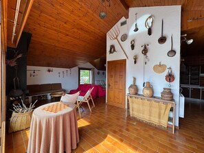 A rustic interior with a wooden ceiling, a dining area with a table and chairs, a sofa, and a wall decorated with various kitchen utensils and pottery. - Casa Els Escolls - Lles de Cerdanya (Lles de Cerdanya)