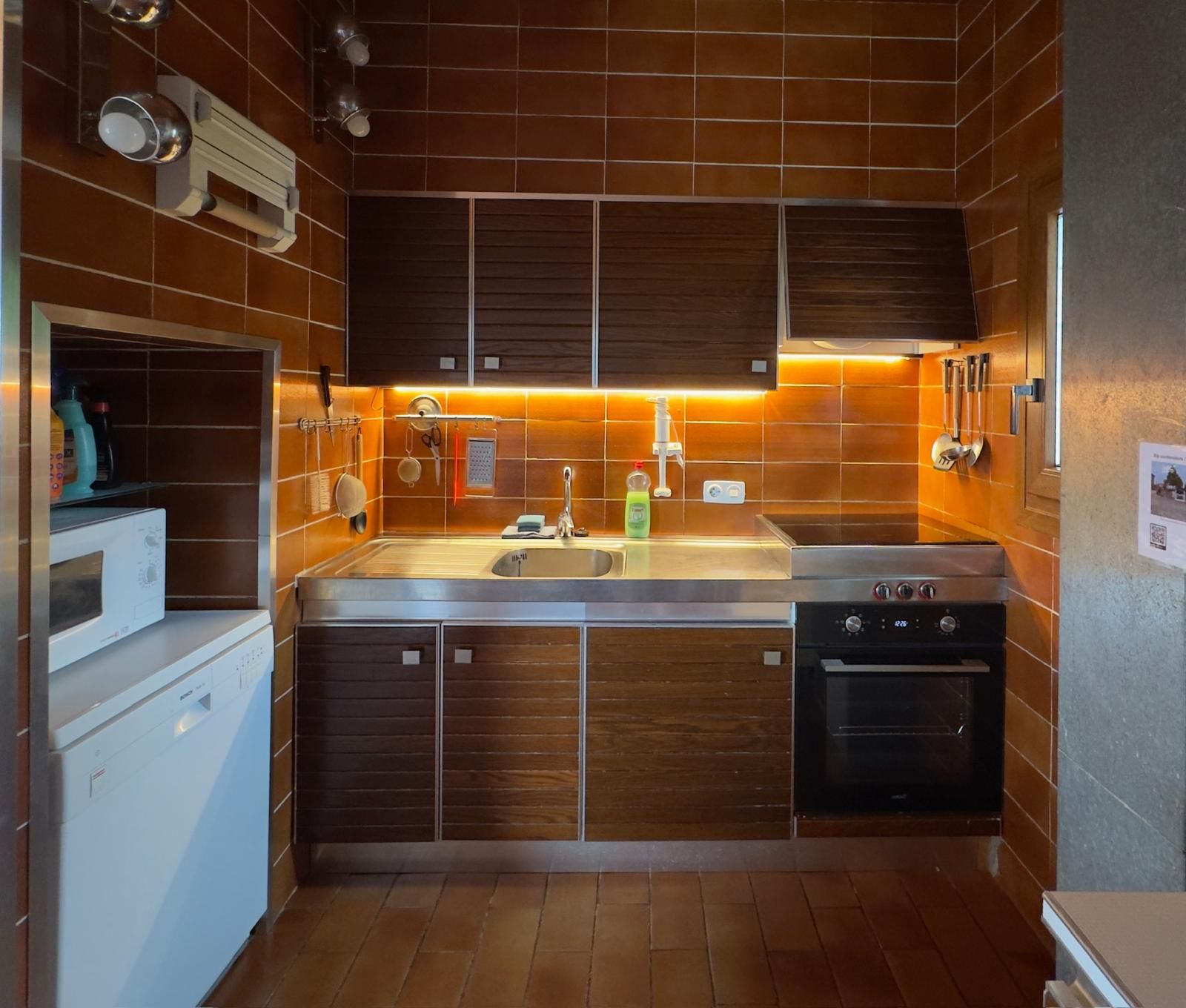 Cozinha compacta com forno embutido, micro-ondas e máquina de lavar louça.