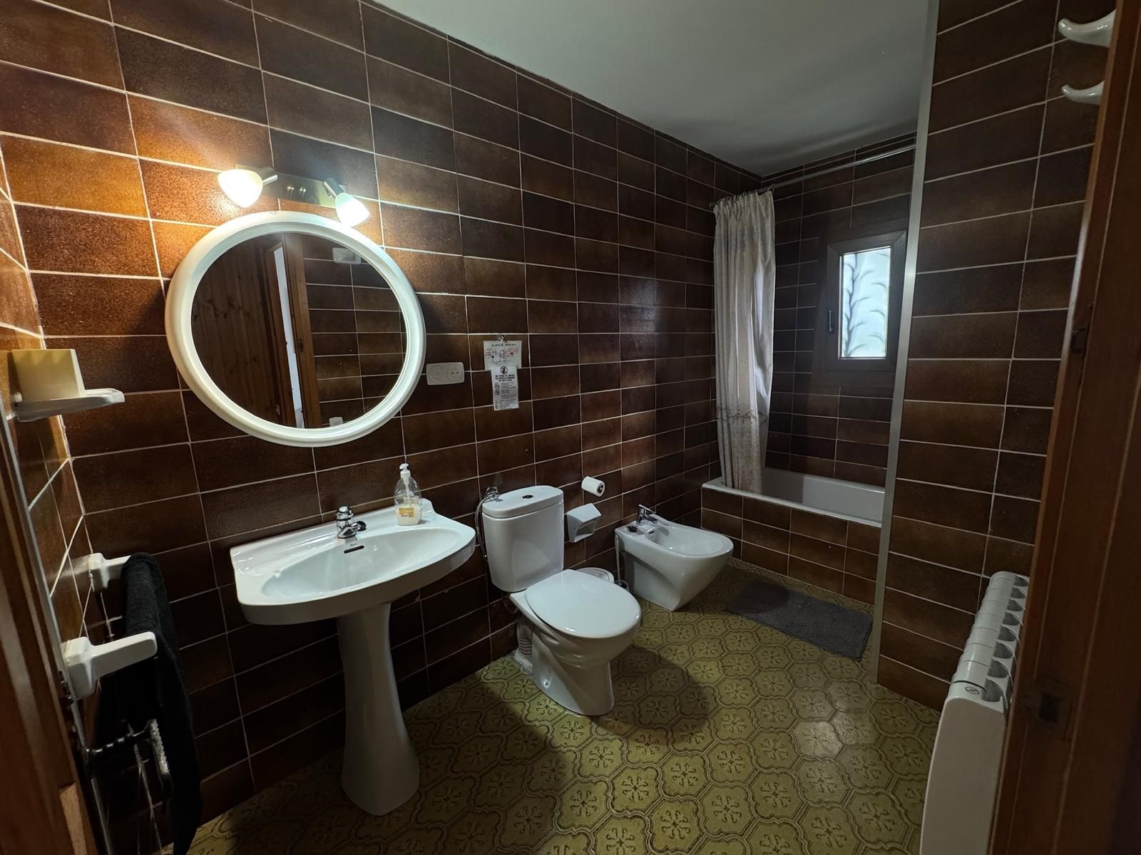 Un baño con lavamanos pedestal, inodoro, bidé y bañera.