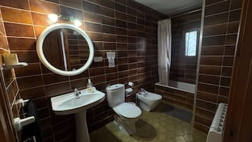 Un baño con lavamanos pedestal, inodoro, bidé y bañera.