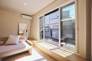 A modern living room with a sofa, a large window, and a view of the outside. - New Listing (新宿区中落合１丁目２１－３  　中落合ホテル)