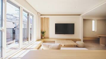 A modern living room with a large TV, wooden furniture, and a view of a building outside.