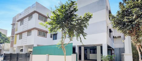 Un edificio moderno con techo plano, ventanas amplias y entrada protegida por una reja.