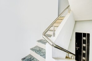 Uma escada com corrimão de metal e uma porta com padrão de grade.