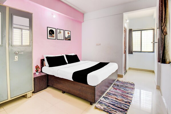 Um quarto com cama, mesa de cabeceira, cômoda, janela e porta.