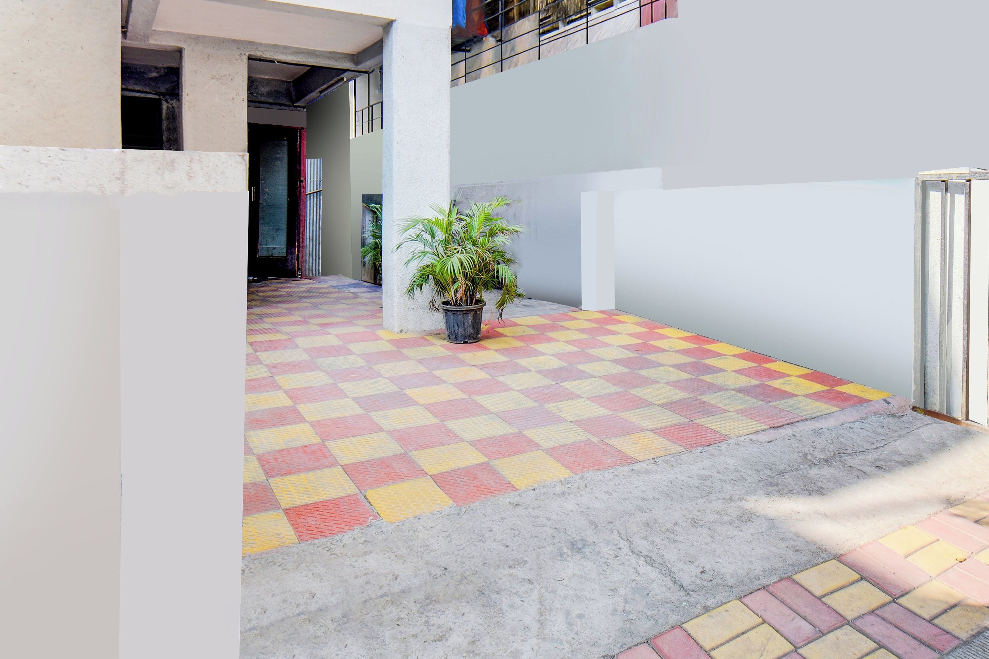 Un couloir avec un sol à motifs à carreaux, une plante en pot et une rambarde en métal.
