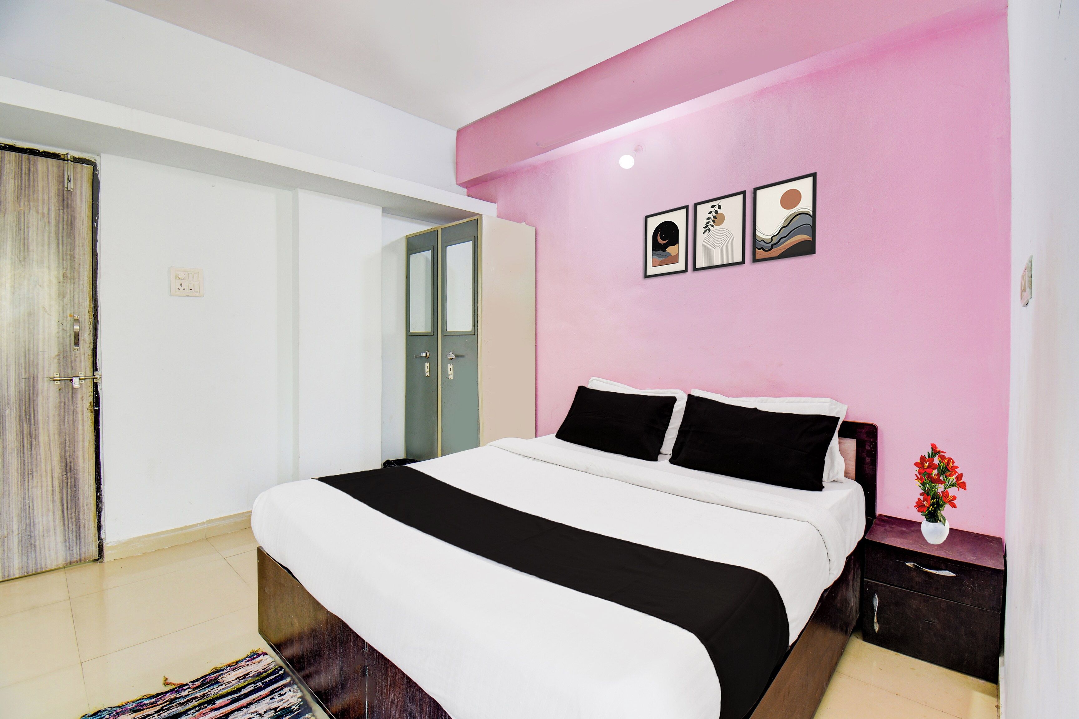 Une chambre à coucher comprenant un lit, une table de chevet, une commode, une porte et un mur orné de trois tableaux encadrés.